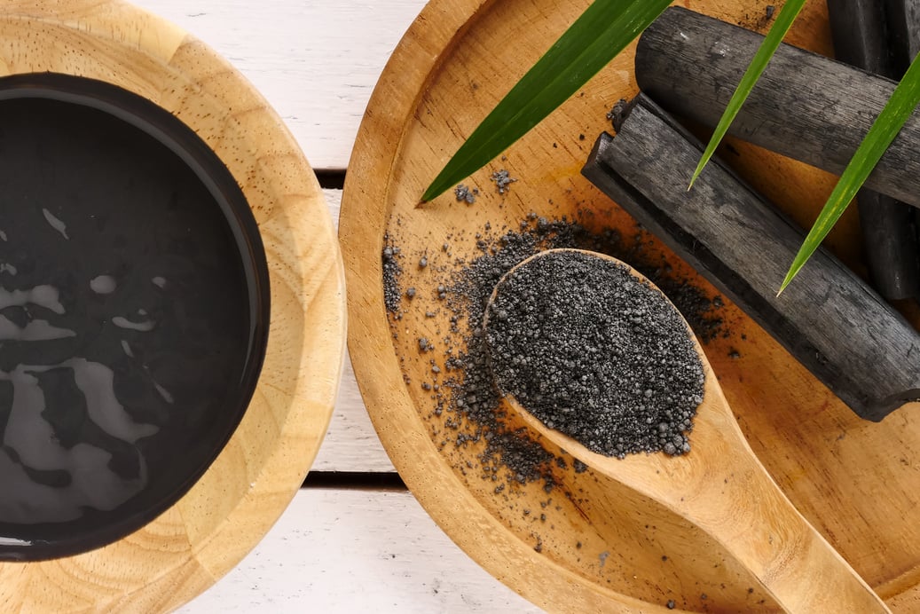 Facial mask and scrub by activated charcoal powder on wooden table
